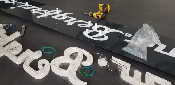 Montage von beleuchteten 3D Buchstaben in der Werkstatt